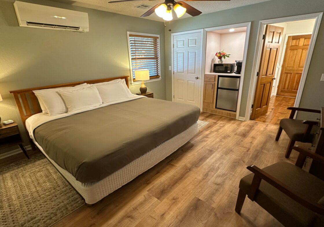 King bed guest room at Cedar Crest Lodge in Pleasanton, KS with kitchenette, mini fridge, and ceiling fan – Painted Desert room