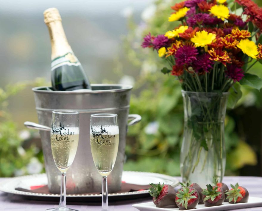 Champagne, chocolate-covered strawberries & flowers on a table outside