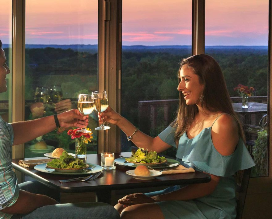 Couple toasting glasses of wine over sunset dinner