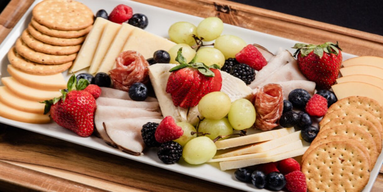 Meat and cheese plate with crackers and strawberries and blueberries