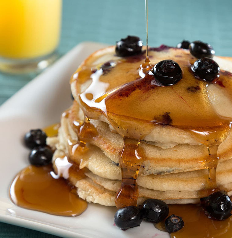 Stack of syrupy pancakes with blueberries