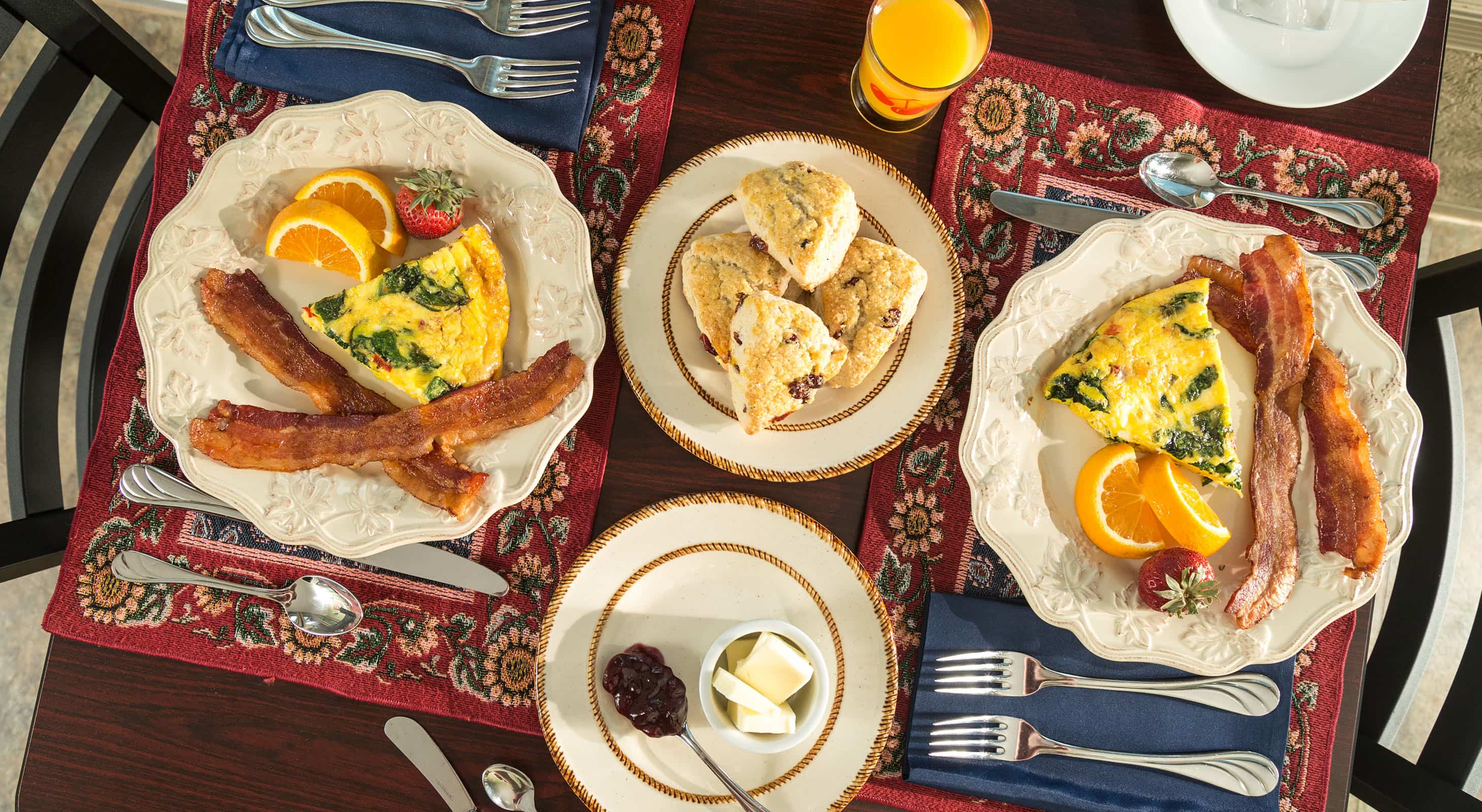 Kansas dining spread of breakfast foods on table with quiche, eggs, bacon, and fresh fruits