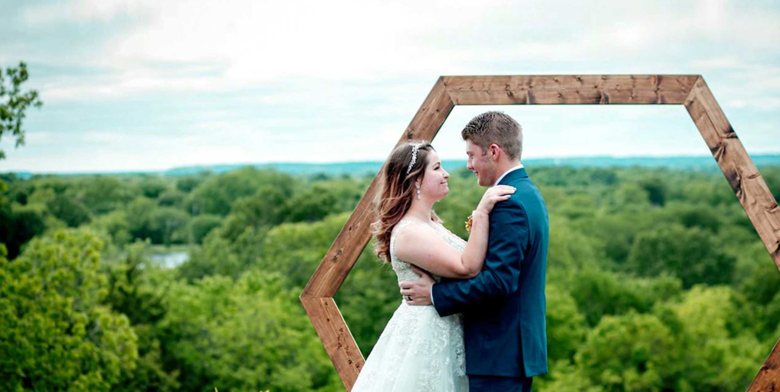 Bride and groom in front of a wooden arch and beautiful views