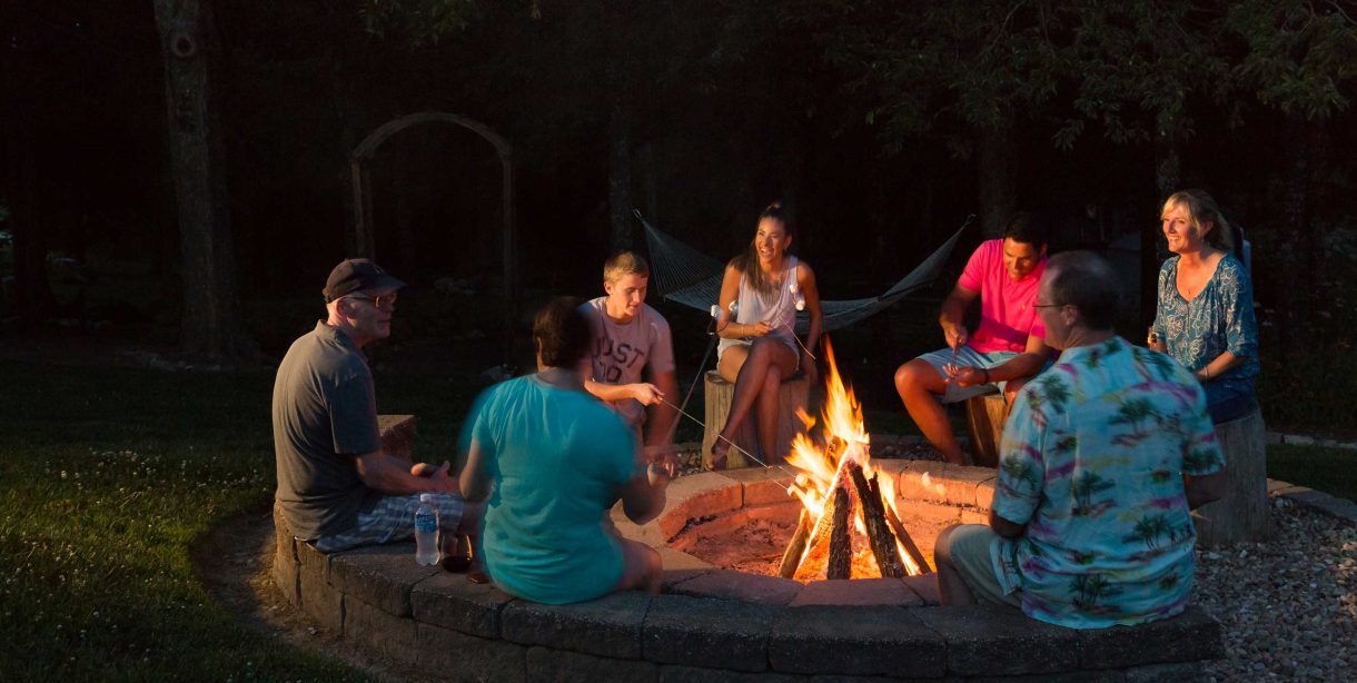 Group of friends sitting around a fire pit at night