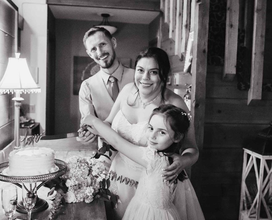 Married couple and child cutting wedding cake
