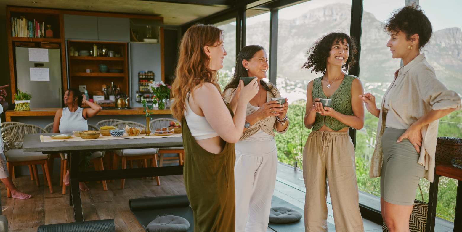 group of women socializing with drinks in cozy kitchen during retreat 