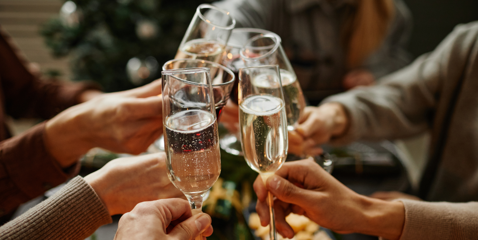 champagne flutes clinking together in a celebratory toast with people in the background