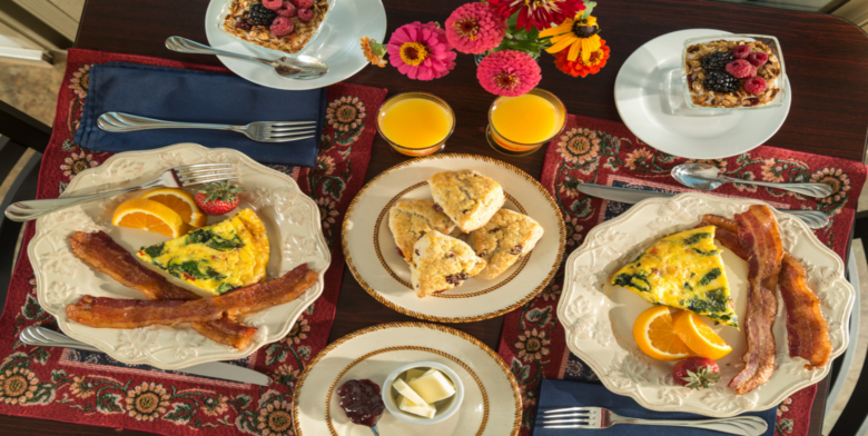 Gourmet breakfast at Cedar Crest Lodge featuring bacon, egg frittata, fresh fruit, scones, and orange juice.